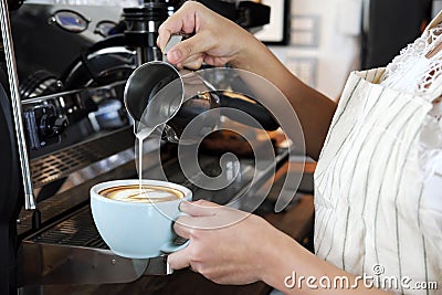 Close-up hand of barista making latte or cappucino coffee in coffee shop. Cafe restaurant service, food and drink industry Stock Photo