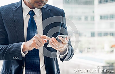 Close up hand of businessman using mobile phone near office wind Stock Photo