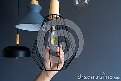 Close-up. A hand changes a light bulb in a stylish loft lamp. Spiral filament lamp. Modern interior decor Stock Photo