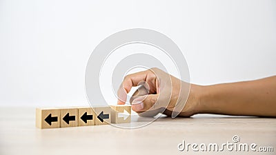 Close-up hand choose cube wooden toy block stacked with arrow icon pointing to opposite directions Stock Photo