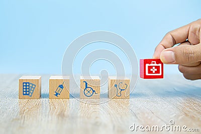 Close-up hand choose Health care and medical symbol icons on wooden toy blocks. Stock Photo