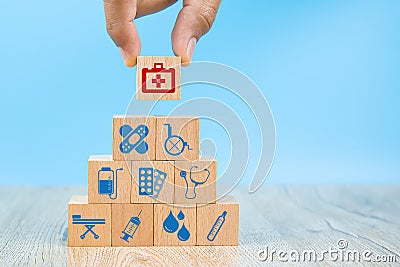 Close-up hand choose Health care and medical symbols on wooden blocks toy stacked in pyramid shape. Stock Photo