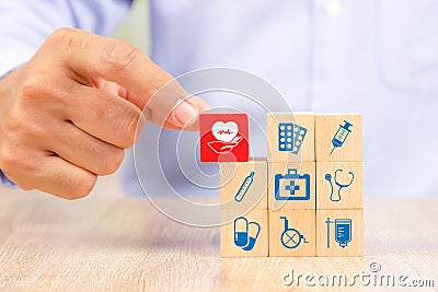 Close-up hand choose wooden toy blocks with medical equipment bag icon for health insurance Stock Photo