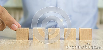 Close-up hand choosing cube wooden block toy stacked without graphics Stock Photo