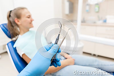 Close-up hand of dentist in the glove holds tool probe and mirror. The patient in the dental chair at the background Stock Photo