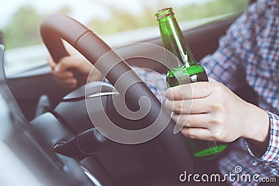 Close up hand Drunk young man while driving a car with a bottle of beer. Don`t drink and drive concept. Driving Stock Photo
