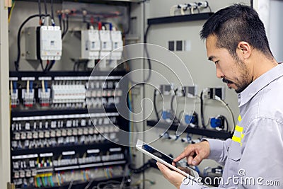 Close up hand of engineer or electrician man working check the electrical system with tablet at factory Stock Photo