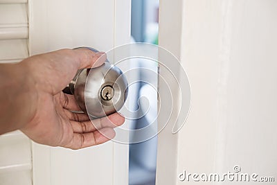Close-up hand holding door knob, opening door slightly, selective focus Stock Photo