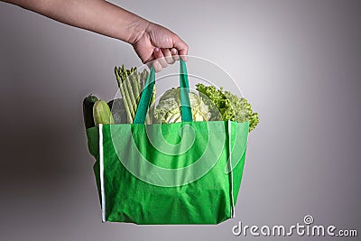 close up hand holding green grocery bag of mixed the organic green vegetables , healthy organic green food shopping and diet heal Stock Photo