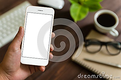 Close up hand holding phone over work table Stock Photo