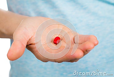 Close-up of hand holding a red pill. Stock Photo