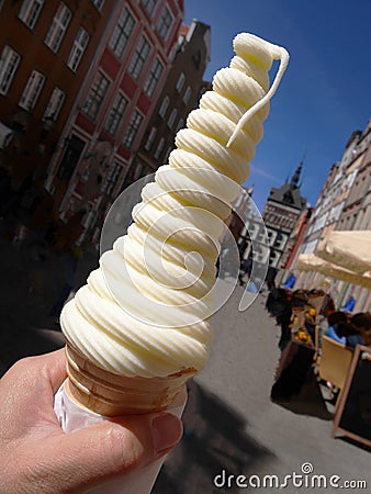 Close up a hand holding tall twist shape soft cream in waffle cone on summer, blurry background Stock Photo