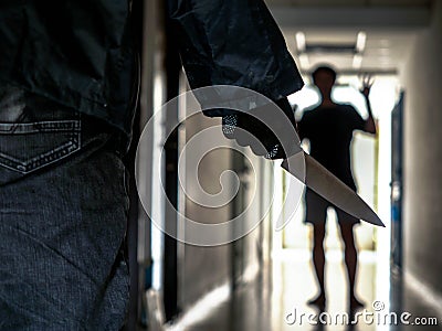 Close up of Hand with knife following young terrified in the apartment. man Bandit is holding a knife in hand, Threat Concept, Stock Photo