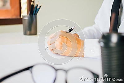 Close up hand lawyer, handwriting civil and criminal indictment on the desk with glasses and coffee working at the home office Stock Photo