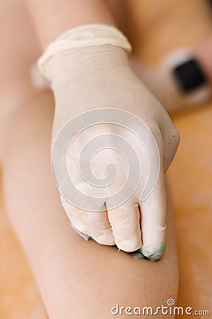 Close-up of a hand that applies a lump of sugar paste for sugaring to the client& x27;s body Stock Photo