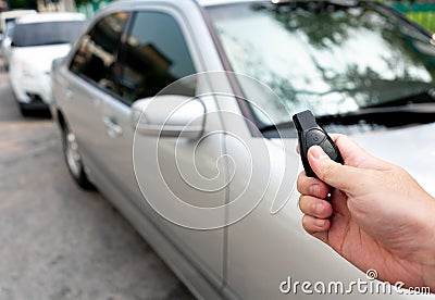 Close up hand press the remote control to unlock or lock car at garage or parking lot. Technology of automotive security system to Stock Photo