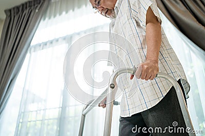 Close up hand of Senior disabled man walk with walker at nursing home. Asian Older elderly handicapped male patient have weak leg Stock Photo