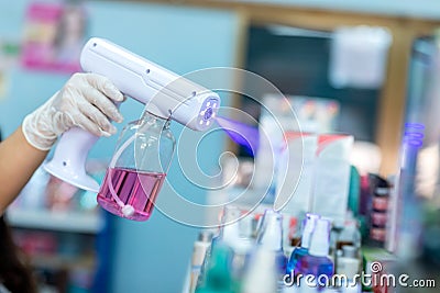 Close up hand of staff wearing gloves using electric Alcohol Nano Spray Gun Handheld Blue Light Disinfection Spray Gun Fogging Stock Photo