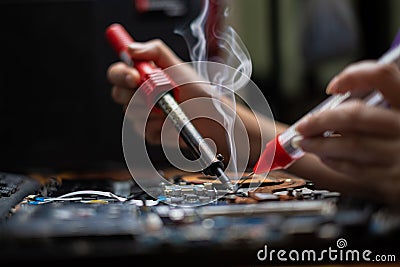 hand technician repairing broken laptop notebook computer with electric soldering Iron Stock Photo