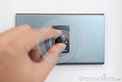 Close up hand turning on grey dimmer switch Stock Photo