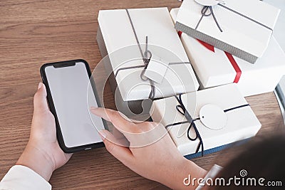 Close-up hand using smartphone for shopping online, gift box on table, shopping for presents Stock Photo