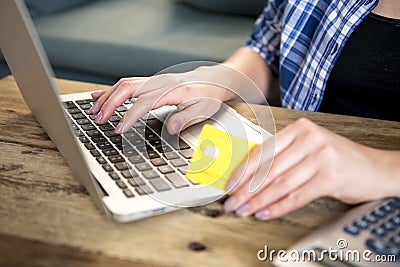 Close up hand of woman holding credit card shopping on line or banking on internet with laptop computer at home in domestic financ Stock Photo