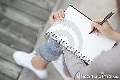 Close up hand young woman are sitting on a marble chair. using pen writing Record Lecture note pad into the book Stock Photo