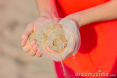 Close-up of a handful of sand in the hands of a young woman Stock Photo