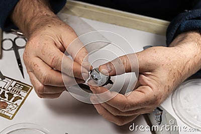 Close up hands of amateur man with age spots, holding plastic part of aircraft, assembled and painted by hand. Stock Photo