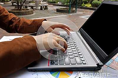 Close up hands of business man typing on laptop in park Stock Photo