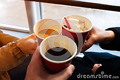 Close up hands with coffee cups at cheers time. friends have fun and drink coffee in the cafeteria Stock Photo