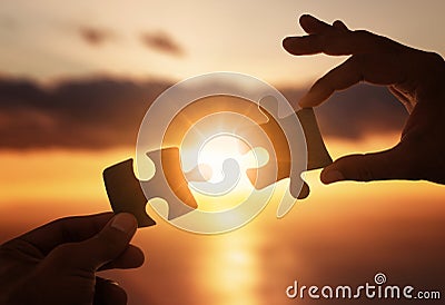Close up of hands connecting two pieces of jigsaw puzzle Stock Photo
