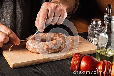 Close-up hands of a cook tying a thread of homemade sausage. Cooking sausages with meat and spices on a cutting board Stock Photo