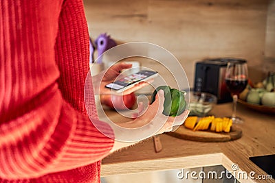 Close-up of the hands of a girl with a mobile phone and vegetables in her hands. Finding a recipe on the Internet and Stock Photo