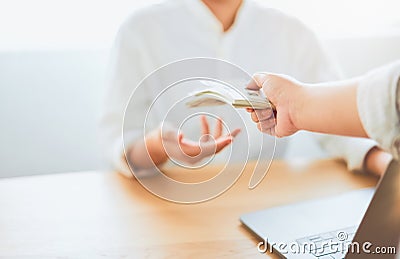 Close-up of hands giving dollar pay compensation from work. Give rewards as incentives for work, on office desk background. Stock Photo