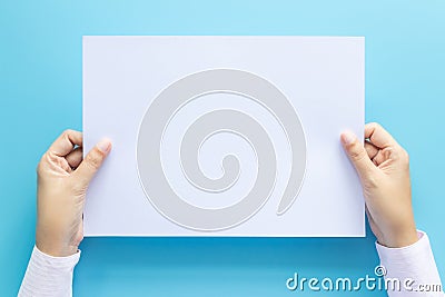 Close up hands holding empty white blank letter paper size A4 for flyer or invitation mock up isolated on a blue background. Stock Photo