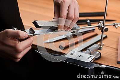 Close-up on hands inserting a whetstone into a manual sharpener machine Stock Photo