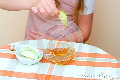 Close up of hands jewish child dipping apple slices into honey on Rosh Hashana. Stock Photo