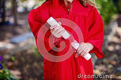 Close-up of Hands of Kindergartner in Red Graduation Gown Stock Photo