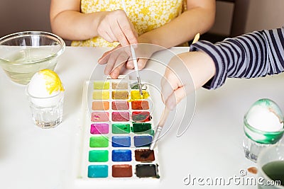 Close-up on the hands of little children who paint eggs with special paints Stock Photo