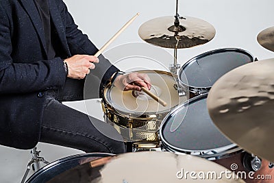 Close up of hands of male drummer holdning drumsticks sitting and playing drums on white background Stock Photo