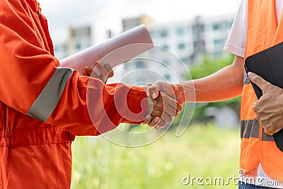 Close up hands of 2 male engineers or construction workers outside with blurred buildings in background Stock Photo