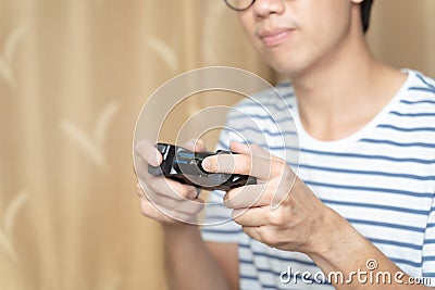 Close up hands of man, gamer using gaming controller or game pad when play video console game or online computer game at home. Stock Photo