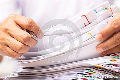 Close-up hands of a man in a white shirt searching for contract agreement documents in Stack of Group report papers clipped in Stock Photo