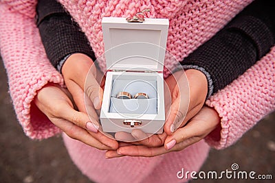 Close-up of the hands of newlywed couple holding white box with gold wedding rings. Winter wedding Stock Photo