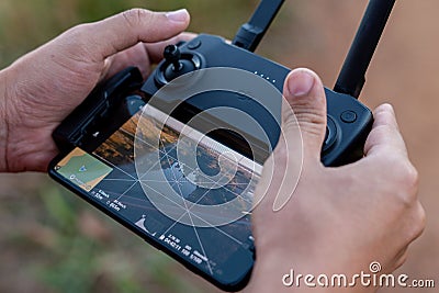Close-up of hands operating a DJI drone controller with a smartphone display showing aerial view Stock Photo
