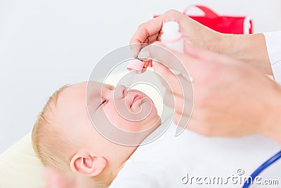 Pediatrician clearing the nose of a baby by applying saline solution Stock Photo