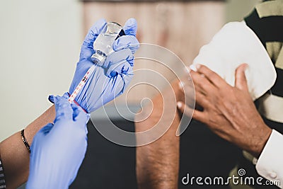 Close up Hands preparing vaccination shot to shoulder of patient - concept of coronavirus or covid-19 vaccine concept. Stock Photo