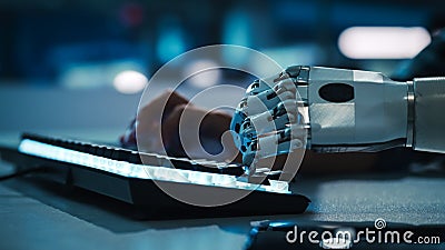Close-up on Hands: Programmer With Disability Using Prosthetic Arm to Work on Backlit Computer Stock Photo