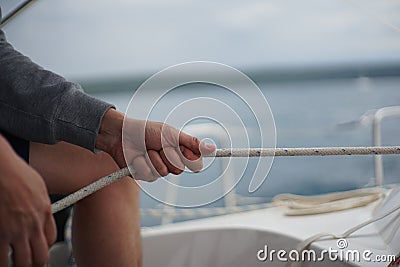 Close up of hands holding a rope, sheet on a sailboat Stock Photo